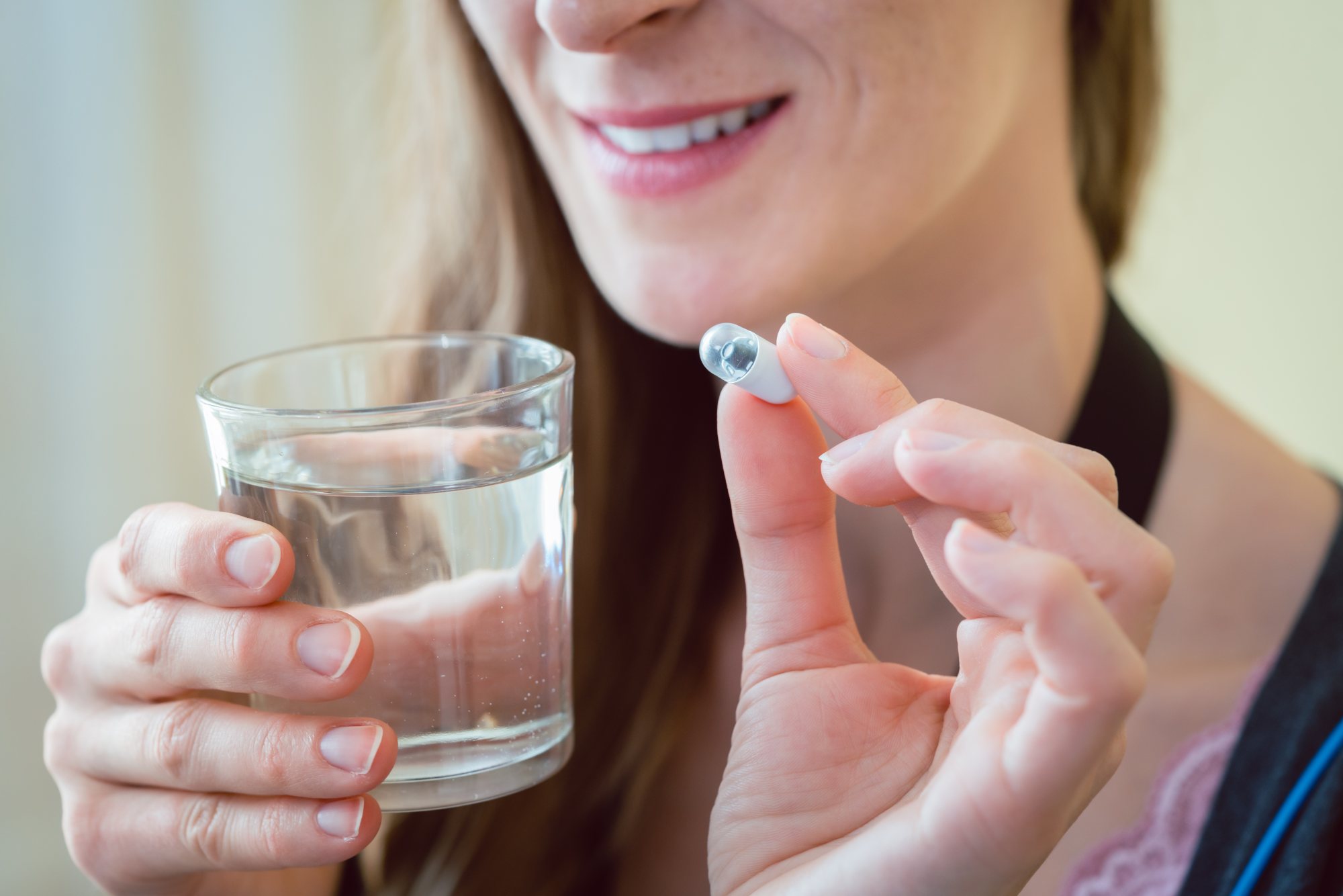 A woman with a glass of water and pill capsule